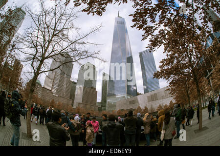 One World Trade Center erhebt sich über Besucher, die National September 11 Memorial & Museum in New York auf Weihnachten, Donnerstag, 25. Dezember 2014. Das Denkmal besteht aus Twin Denkmal Pools auf den Spuren des World Trade Center und ein Platz mit mehr als 400 Sumpf weißer Eiche Bäume gepflanzt. Die Namen der 2983 Opfer von 9/11 und der Februar 1993 WTC Angriff um die Basis der Pools eingeschrieben sind. (© Richard B. Levine) Stockfoto