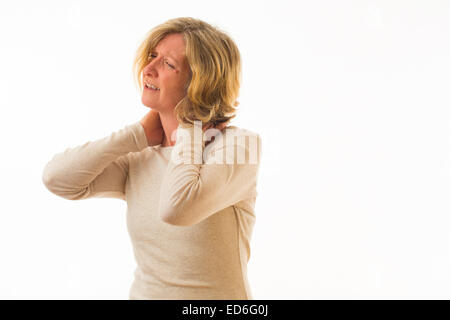 Eine vierzig Jahre alten kaukasischen Frau leidet Hals Schmerz reiben ihren Hals zur Schmerzlinderung, vor einem weißen Hintergrund. UK Stockfoto