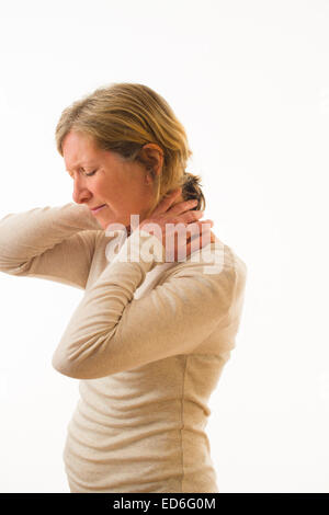 Eine vierzig Jahre alten kaukasischen Frau leidet Hals Schmerz reiben ihren Hals zur Schmerzlinderung, vor einem weißen Hintergrund. UK Stockfoto