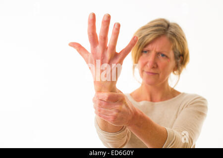 Eine vierzig Jahre alten kaukasischen Frau mit schmerzhaften Arthrosen in den Gelenken von ihr Handgelenk und den Fingern, rieb ihr Handgelenk zur Schmerzlinderung, vor einem weißen Hintergrund. UK Stockfoto