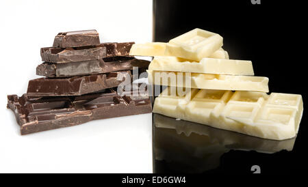Stücke von dunkler Schokolade auf einem weißen Hintergrund und weißer Schokolade auf einem schwarzen Hintergrund Stockfoto