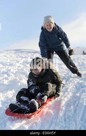 Lifestyle-Schuss älteres Ehepaar mit ihrem Enkel im Schnee Rodeln. Stockfoto