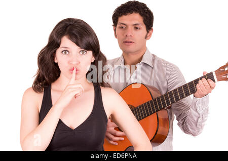 schöne Mädchen gestikulieren Stille während der junge Mann ihr Ständchen mit Gitarre Stockfoto