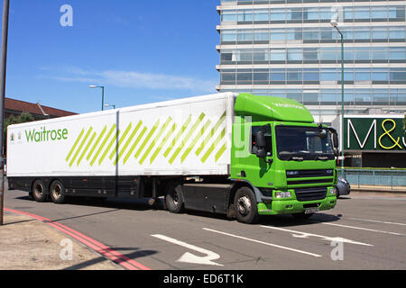 Ein Waitrose LKW um einen Kreisverkehr in Tolworth, Surrey, England reisen. und vorbei an einer M & S-Zeichen Stockfoto