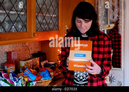 zwölf Jahre altes Mädchen Sahnetorte in einer Box mit einem schuldig Ausdruck auf ihrem Gesicht zu betrachten Stockfoto