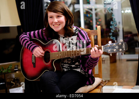 zwölf Jahre alte Mädchen spielt Gitarre für ihre Familie zur Weihnachtszeit Stockfoto