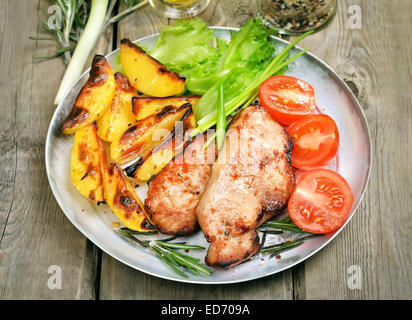 Gegrilltes Steak mit Bratkartoffeln und frisches Gemüse auf rustikalen Tisch Stockfoto
