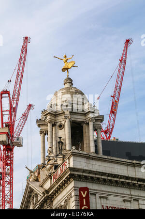 Kraniche über dem Dach des Victoria Palace Theatre in London.  Die vergoldete Statue der Anna Pavlova sitzt oben auf der Kuppel. Stockfoto