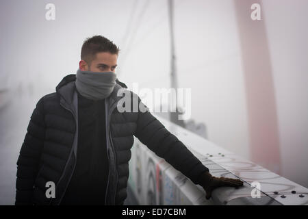 Junger Mann im Winter Mode stehen im Freien mit Schal versteckt sein Gesicht Stockfoto