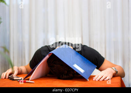 Müde, erschöpft oder mutlos junger Mann mit einem Ordner über den Kopf Stockfoto