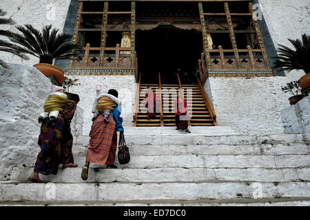 Buddhistische Anhänger betreten die Festung Punakha Dzong aus dem 17. Jahrhundert, auch bekannt als Pungtang Dechen Photrang Dzong, das Verwaltungszentrum des Distrikts Punakha im Punakha-Tal, Bhutan Stockfoto