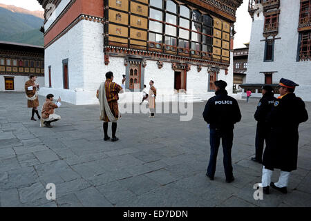 Die Polizei beobachtet die Besucher, die im Hof von Tashichho Dzong posieren Festung Sitz der Regierung Bhutans seit 1952 und derzeit Häuser Der Thronsaal und die Büros des Königs auf dem Rand der Stadt Thimphu in Bhutan Stockfoto