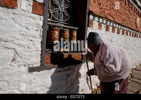 Ein buddhistischer Anhänger dreht Gebetsräder, während er die umkreist Buddhistischer Jambay Lhakhang oder Tempel von Maitreya einer der 108 Tempel, die vom tibetischen König Songtsen Goenpo in erbaut wurden 659 n. Chr. in der Nähe der Stadt Bumthang in Bhutan Stockfoto