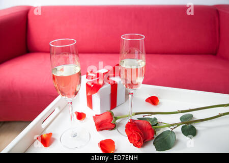 Sektgläser und rote Rose im Wohnzimmer Stockfoto