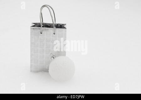 Silber Geschenktüte mit Weihnachtskugel im Schnee, horizontale Stockfoto