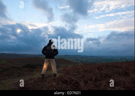 Mynydd Epynt, Powys, UK. 31. Dezember 2014. Eine Hügel Walker schaut die Sonne hinter Wolken in einem ominösen Himmel zum letzten Mal im Jahr 2014. Bildnachweis: Graham M. Lawrence/Alamy Live-Nachrichten. Stockfoto