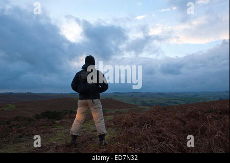 Mynydd Epynt, Powys, UK. 31. Dezember 2014. Eine Hügel Walker schaut die Sonne hinter Wolken in einem ominösen Himmel zum letzten Mal im Jahr 2014. Bildnachweis: Graham M. Lawrence/Alamy Live-Nachrichten. Stockfoto