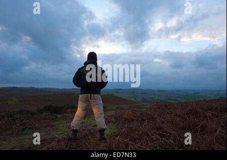 Mynydd Epynt, Powys, UK. 31. Dezember 2014. Eine Hügel Walker schaut die Sonne hinter Wolken in einem ominösen Himmel zum letzten Mal im Jahr 2014. Bildnachweis: Graham M. Lawrence/Alamy Live-Nachrichten. Stockfoto