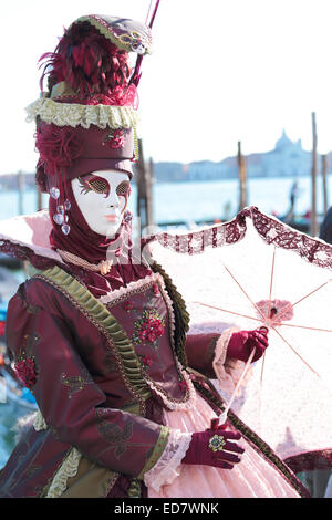 Eine rote maskierte Dame mit Sonnenschirm Regenschirm ausgestellt, während das traditionelle Fest der Karneval von Venedig, Italien (2014-Ausgabe) Stockfoto