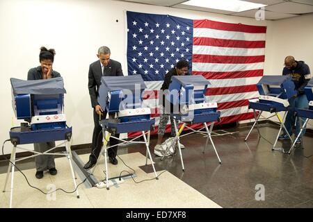 US-Präsident Barack Obama wirft seinen Stimmzettel während der frühen Abstimmung an der Martin Luther King Jr. Community Center 20. Oktober 2014 in Chicago, IL. Anderen Wähler Mike Jones, ganz rechts, witzelte "Mr. President, berühren Sie nicht meine Freundin" Wenn der Präsident fertig abstimmen, er streckte und gab Cooper einen Kuss auf die Wange. Stockfoto