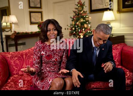 UNS, die First Lady Michelle Obama zu halten ein ernstes Gesicht versucht während der Aufzeichnung der Urlaub Nachricht als Präsident Barack Obama in Lachen in der Map Room des weißen Hauses 19. November 2014 in Washington, DC bricht aus. Stockfoto