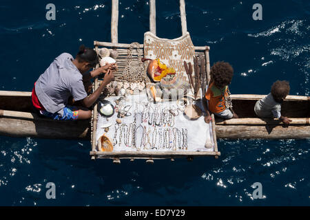 Melanesien, Papua Neu Guinea, Tufi. Dorfbewohner in hölzernen Einbaum mit Ausleger verkauft Muscheln und Kunsthandwerk. Stockfoto