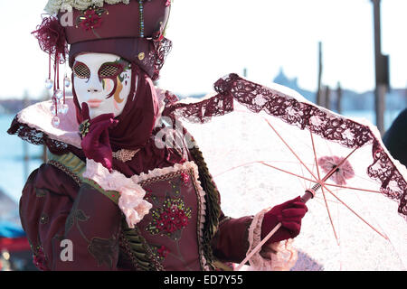 Eine rote maskierte Dame mit Sonnenschirm Regenschirm ausgestellt, während das traditionelle Fest der Karneval von Venedig, Italien (2014-Ausgabe) Stockfoto