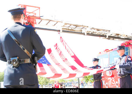 Ein Polizist mit der amerikanischen Flagge, die von einer Feuerwehr Leiter aufgehängt Stockfoto