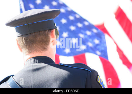 Menomonee Falls Polizist begrüßte die amerikanische Flagge, die von einer Feuerwehr Leiter aufgehängt Stockfoto