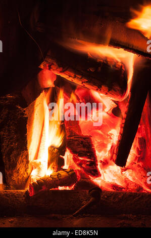 Herzlich Leuchten einer traditionellen Winter-Szene wie am offene Feuer in einem Haus leuchtende Licht strahlt, wie Holz Glut und Kohle heiß verbrennen Stockfoto