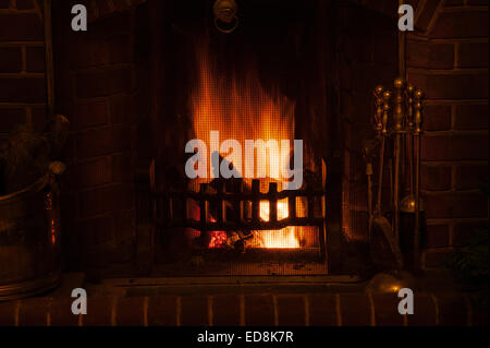 Herzlich Leuchten einer traditionellen Winter-Szene wie am offene Feuer in einem Haus leuchtende Licht strahlt, wie Holz Glut und Kohle heiß verbrennen Stockfoto