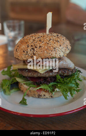 Australische Hamburger mit 'Lot' (Salat, Tomate, Zwiebel, Käse, Speck, Spiegelei und rote Beete) auf einem bestreute Brötchen serviert. Stockfoto
