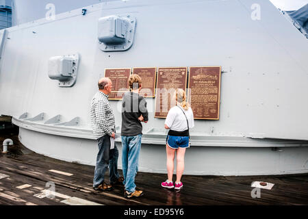 Ein Vater mit seinen Kindern lesen die Widmung Plaques auf einen Geschützturm des Schlachtschiffes USS Alabama befindet sich in der Gedenkstätte Par Stockfoto