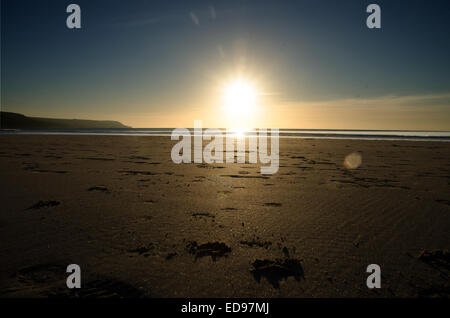 Sonnenuntergang über dem Meer mit Fussspuren im sand Stockfoto