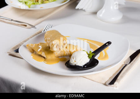Leckere frische Backwaren Dessert mit einer süßen Füllung beträufelt mit Vanillesauce, serviert mit würziger Zitrone Sorbet oder Vanille-Eis-crea Stockfoto