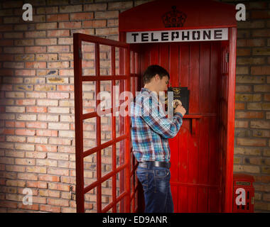 Mann stand in einer roten britische Telefonzelle anrufen mit einem Vintage DFÜ-instrument Stockfoto