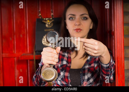 Junge Frau zeigt einen eingehenden Anruf, wie sie eine Vintage Mobilteil in Richtung der Zuschauer und Punkten dabei mit dem Finger hält Stockfoto