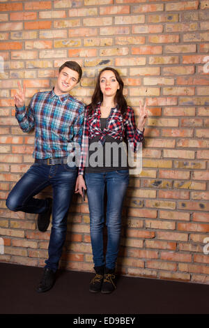 Voller Länge Erfassung der jungen weißen paar in Casual-Outfit stützte sich auf Mauer und schaut in die Kamera. Stockfoto