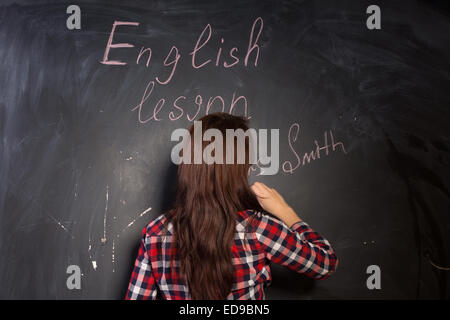Mrs Smith sich der Klasse vorstellen, wie sie eine englische-Lektion in der Schule ihren Namen an die Tafel zu schreiben, mit ihr beginnt zurück in die Kamera. Stockfoto