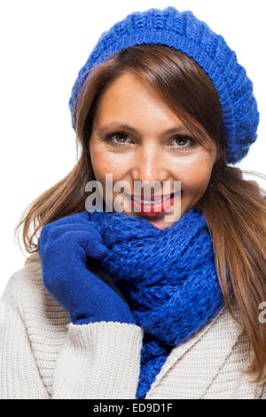 Schließen Sie sich ziemlich lächelnde junge Frau tragen stricken Winteroutfit mit blauer Mütze, Schal und Handschuhe. Aufgenommen im Studio mit weiß Stockfoto