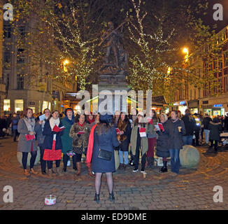 Traditionelle Carol Singers Manchester St Annes Sq, England, UK in der Nacht Stockfoto