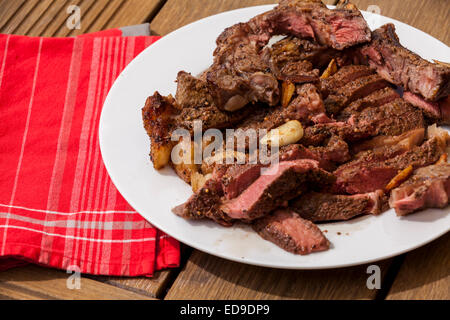 Teller mit in Scheiben geschnittenen gegrilltes Steak und Knoblauch mit roten Serviette Stockfoto