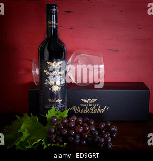 Australische Premium Export Qualitätswein mit Flaschen von Wolf Blass Gold und schwarz Etikett Wein auf dunkelroten Hintergrund Holz Stockfoto