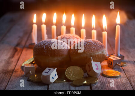 Jüdischer Feiertag Hannukah Symbole - Menora, Krapfen, Schokoladen-Münzen und Holz Dreidel. Stockfoto