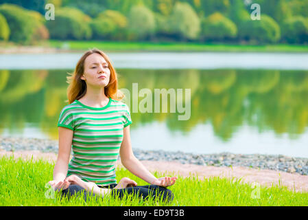 Mädchen im Lotussitz beim Yoga auf die Natur konzentriert Stockfoto