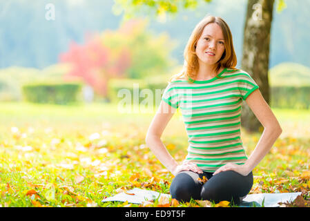 junges Mädchen im Herbst Park am Morgen Yoga zu praktizieren Stockfoto