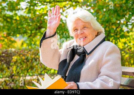 Glückliche grauhaarige Frau von 80 Jahren mit einem Buch Stockfoto