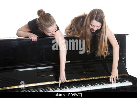 zwei Mädchen im Teenageralter und schwarze Klavier im Studio vor weißem Hintergrund Stockfoto