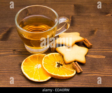 Tee und Gebäck mit Orange und Zimt auf Holztisch Stockfoto
