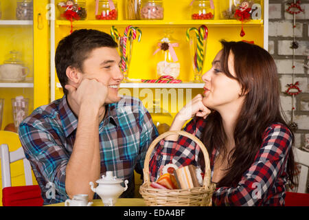 Junge weiße Brautpaar in Casual Outfits auf der Suche nach einander mit den Händen auf ihrem Gesicht während Sie mit einem Date im Cafe hautnah. Stockfoto